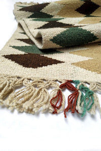 Close up of Cream colored XG Wool Tapestry with Dark Brown and Green Diamond Pattern with Cream Fringe.
